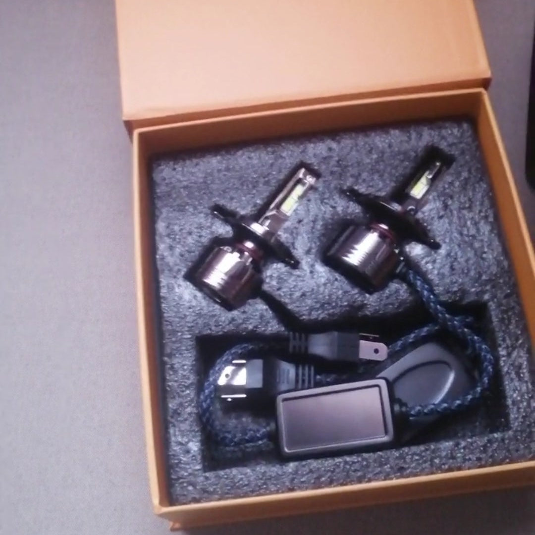 Car headlights and related components in an open box on a gray surface